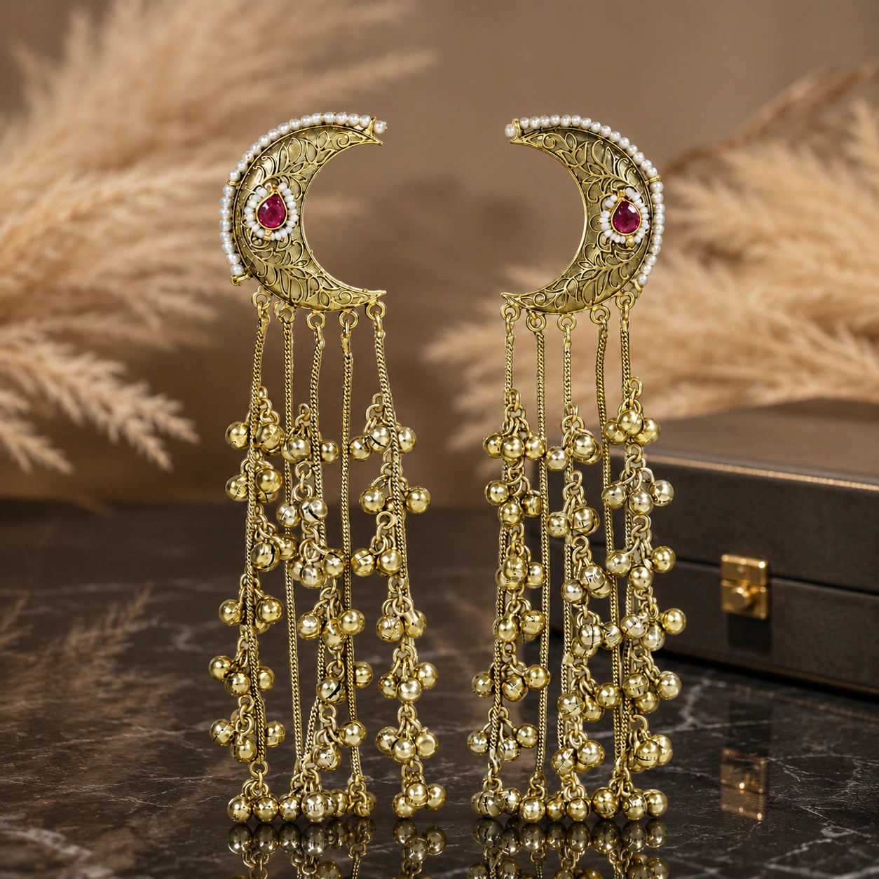 Gold-tone Kundan-style chandbali earrings on a glossy dark reflective jewellery display