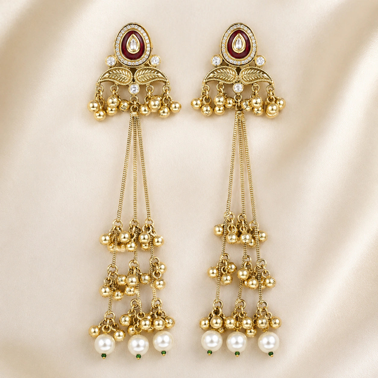 Angled view of gold-tone Kundan pearl chandelier earrings with layered drops