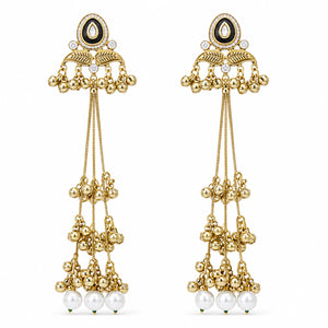 Gold-tone Kundan-style pearl tassel earrings on a dark reflective jewellery display