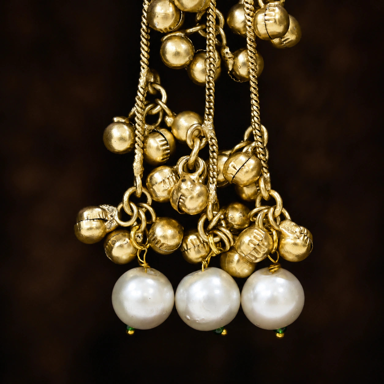 Gold-tone Kundan-style pearl tassel statement earrings worn by a model