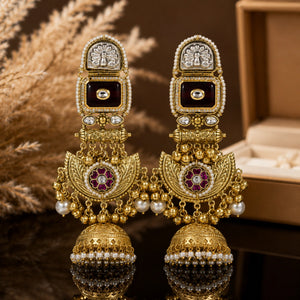 Gold-tone maroon chandbali earrings on a glossy dark reflective jewellery display