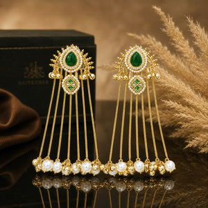Gold-tone pearl tassel statement earrings on a glossy dark reflective jewellery display