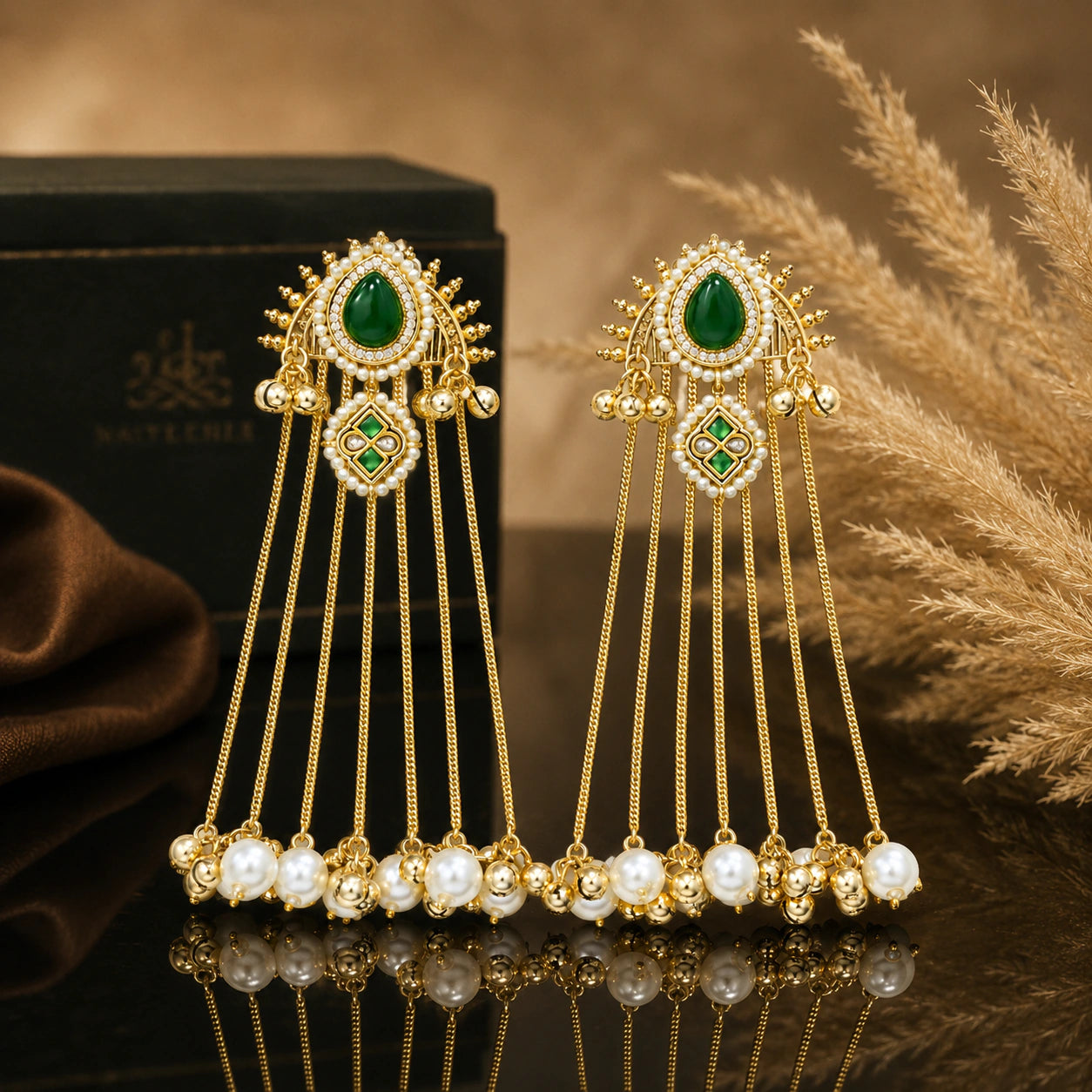 Gold-tone pearl tassel statement earrings on a glossy dark reflective jewellery display