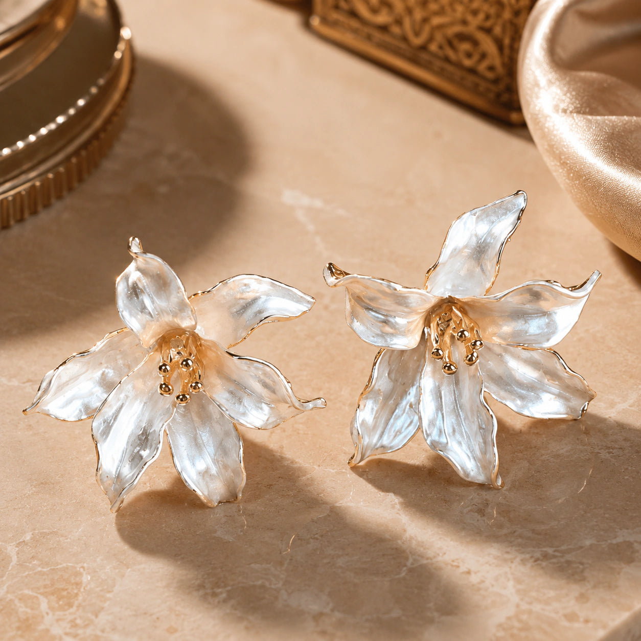 Angled view of pearl-white gold-edged sculptural floral earrings
