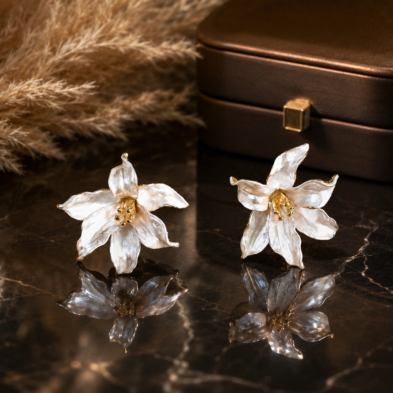 Pearl-white gold-edged floral statement earrings on a dark jewellery studio display