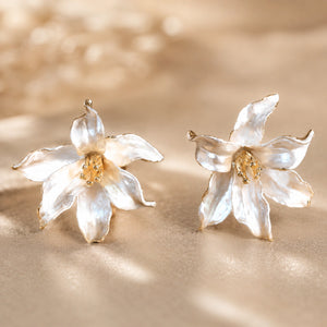 Pearl-white gold-edged floral earrings styled in an elegant jewellery flat lay