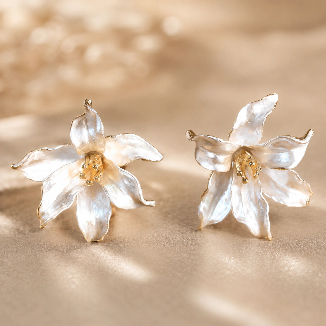 Pearl-white gold-edged floral earrings styled in an elegant jewellery flat lay