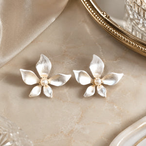 Angled view of pearl-white gold-tone floral push-back earrings