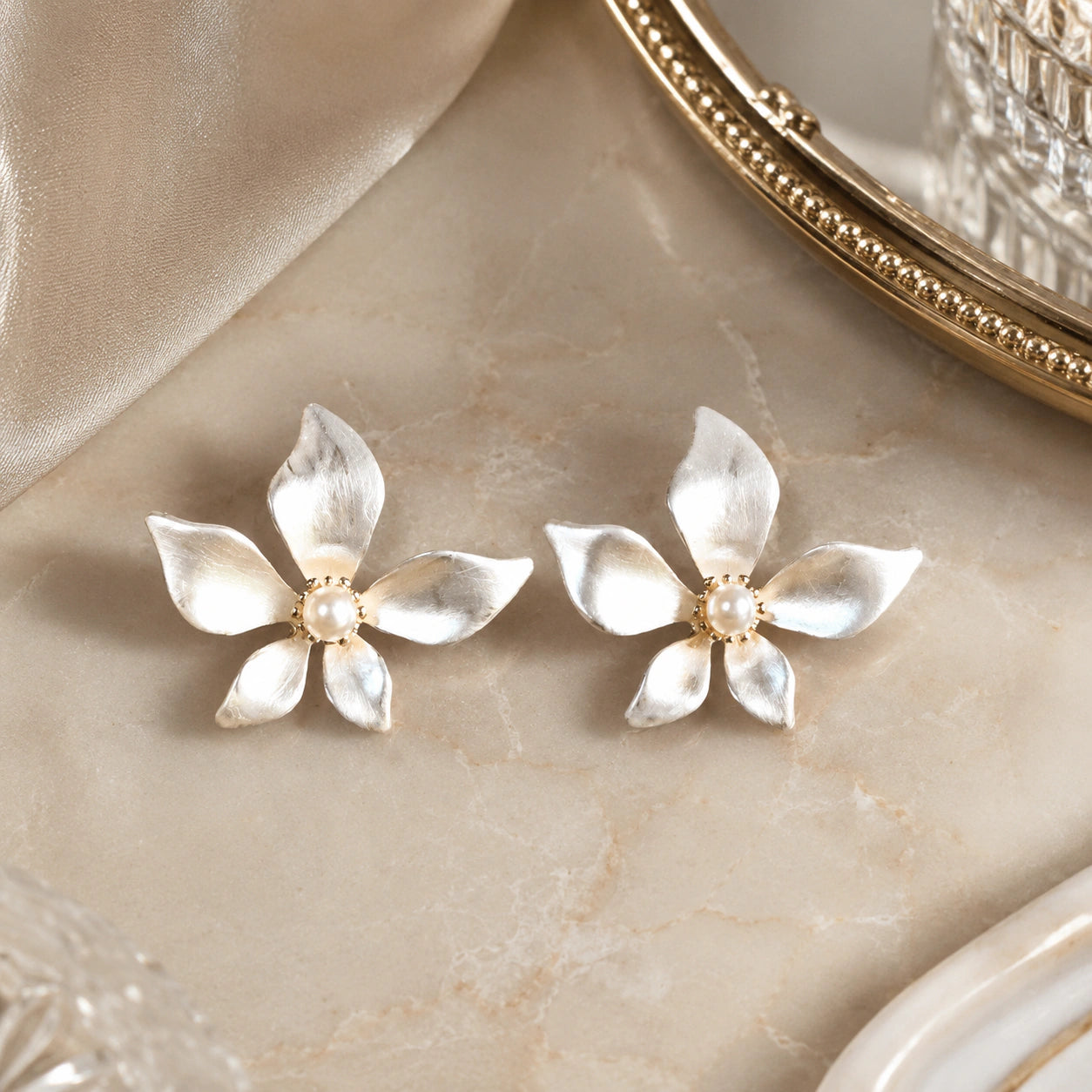 Angled view of pearl-white gold-tone floral push-back earrings