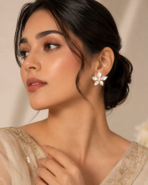 Pearl-white gold-tone floral earrings worn by a model