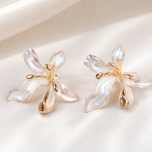 Angled view of pearl-white leaf floral gold-tone drop earrings