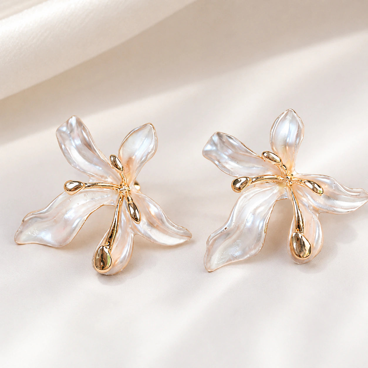 Angled view of pearl-white leaf floral gold-tone drop earrings
