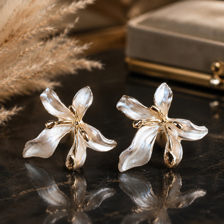 Pearl-white leaf floral earrings on a dark jewellery studio display