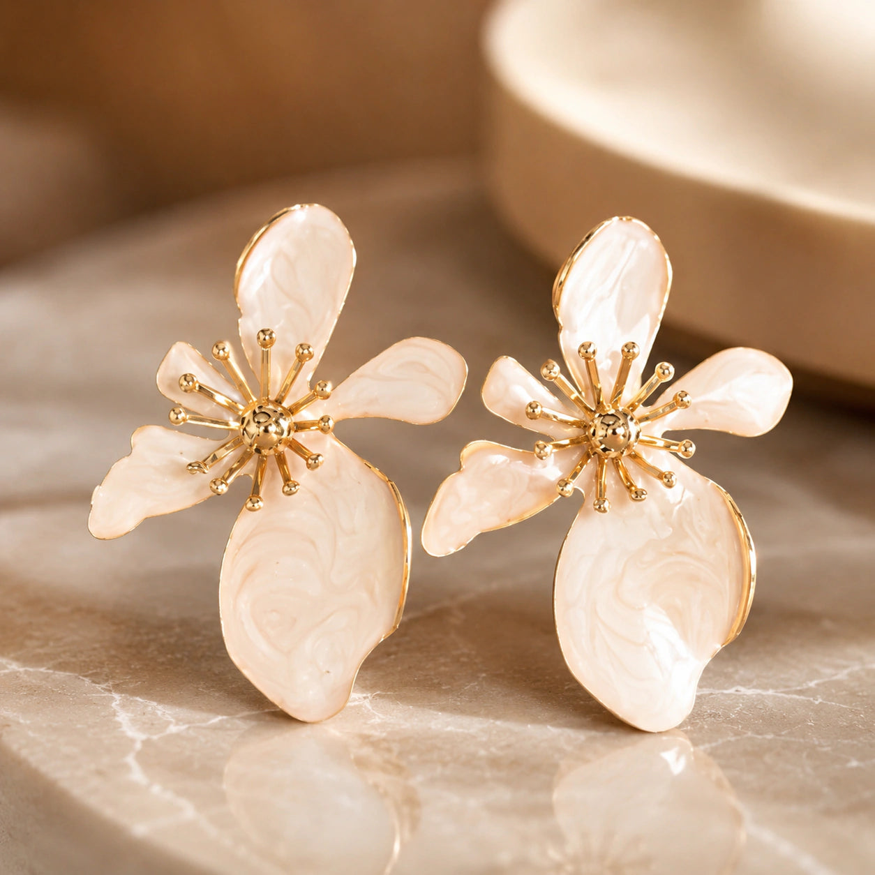 Angled view of pearl-white marbled floral gold-tone drop earrings
