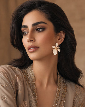 Pearl-white marbled floral gold-tone earrings worn by a model