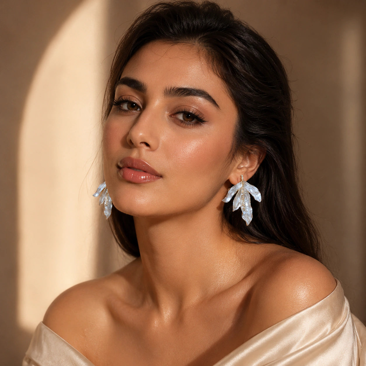 Pearl-white sculptural leaf earrings styled in an elegant jewellery flat lay