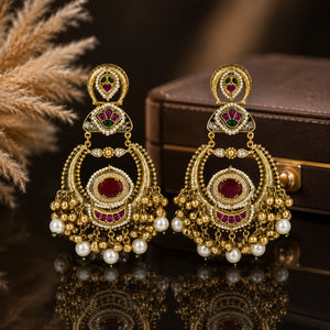 Red-stone pearl chandbali earrings on a glossy dark reflective jewellery display