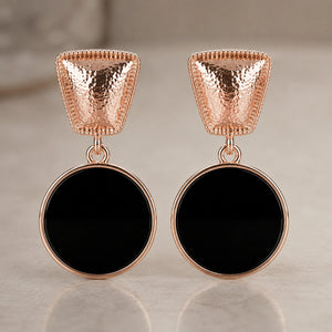 Rose-gold black disc earrings styled in a modern jewellery flat lay