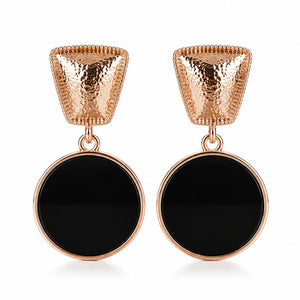Close-up of textured rose-gold tops and black disc pendants