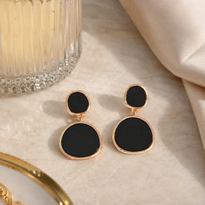 Rose-gold black inlay earrings styled in a modern jewellery flat lay