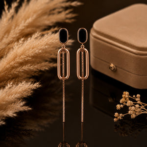 Angled view of rose-gold black oval-chain dangle earrings