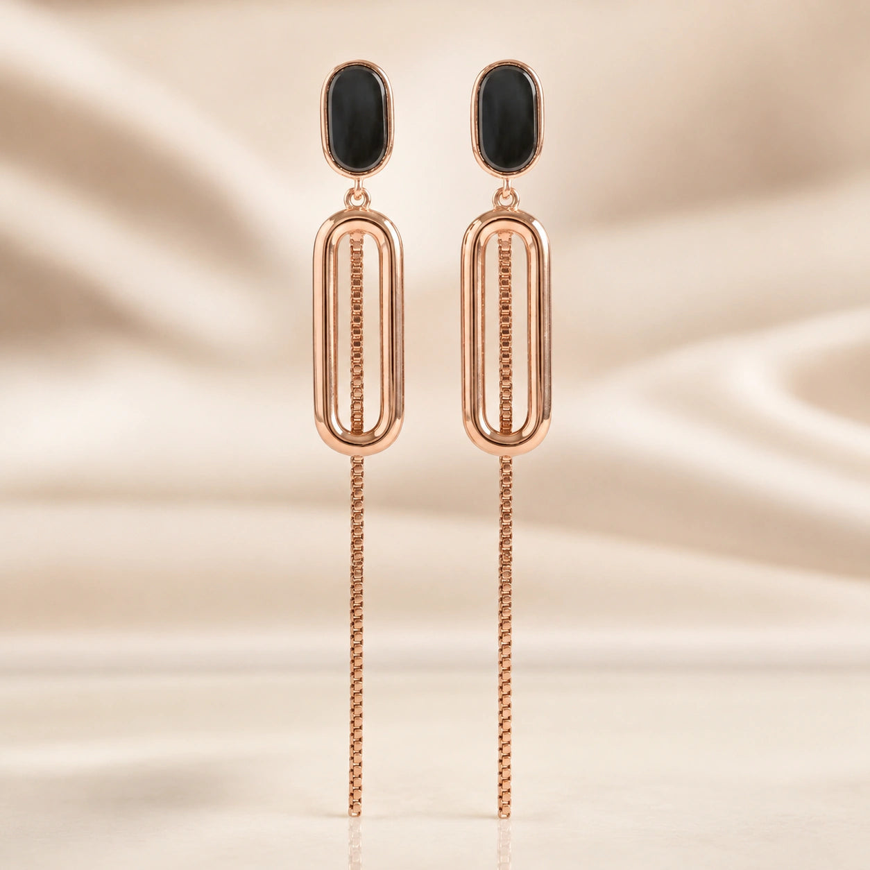 Rose-gold black oval-chain earrings styled in an elegant jewellery flat lay