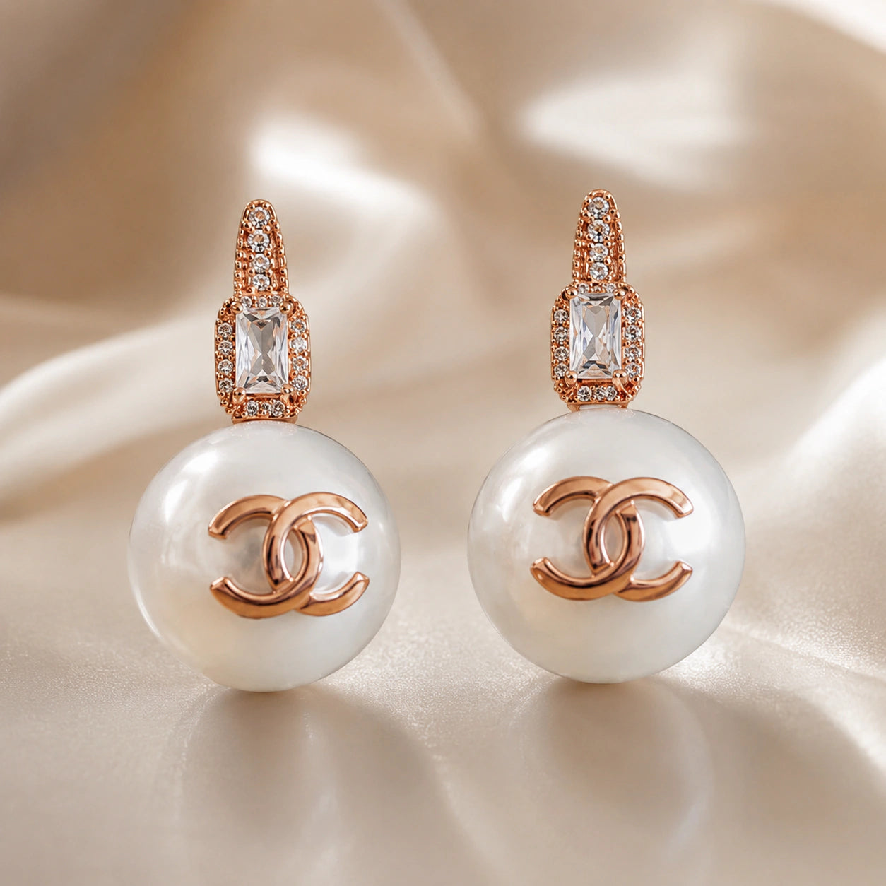 Rose-gold pearl emblem earrings styled in an elegant jewellery flat lay