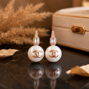 Close-up of pearl-style drops and rose-gold emblem detailing