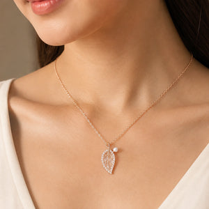 Rose-gold pearl leaf necklace on a dark jewellery studio display