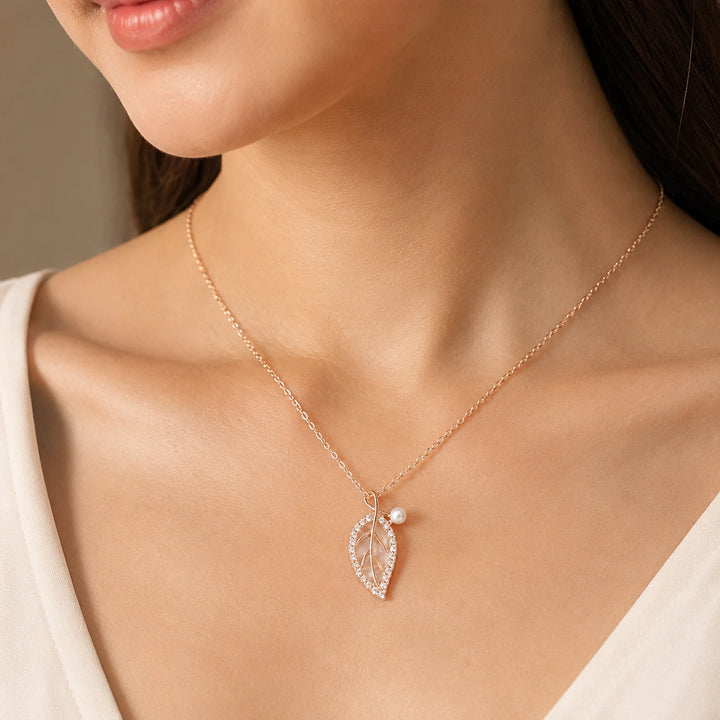 Rose-gold pearl leaf necklace on a dark jewellery studio display