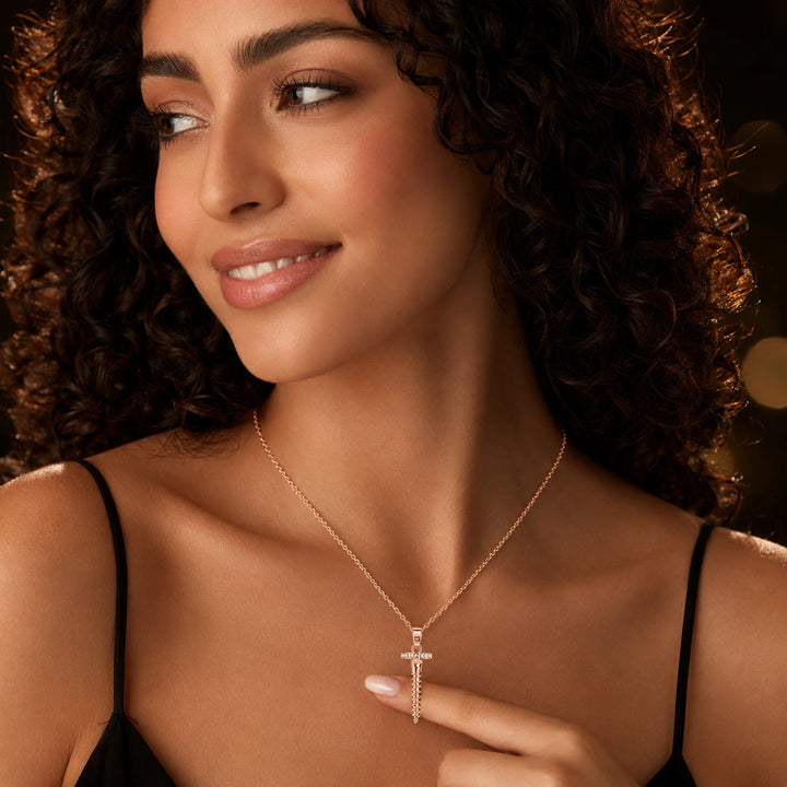 Rose-gold screw charm necklace on a dark jewellery studio display