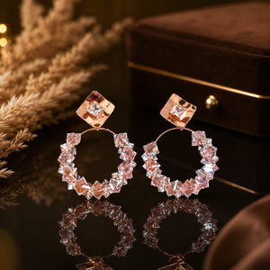 Angled view of rose-gold square crystal cluster hoop earrings
