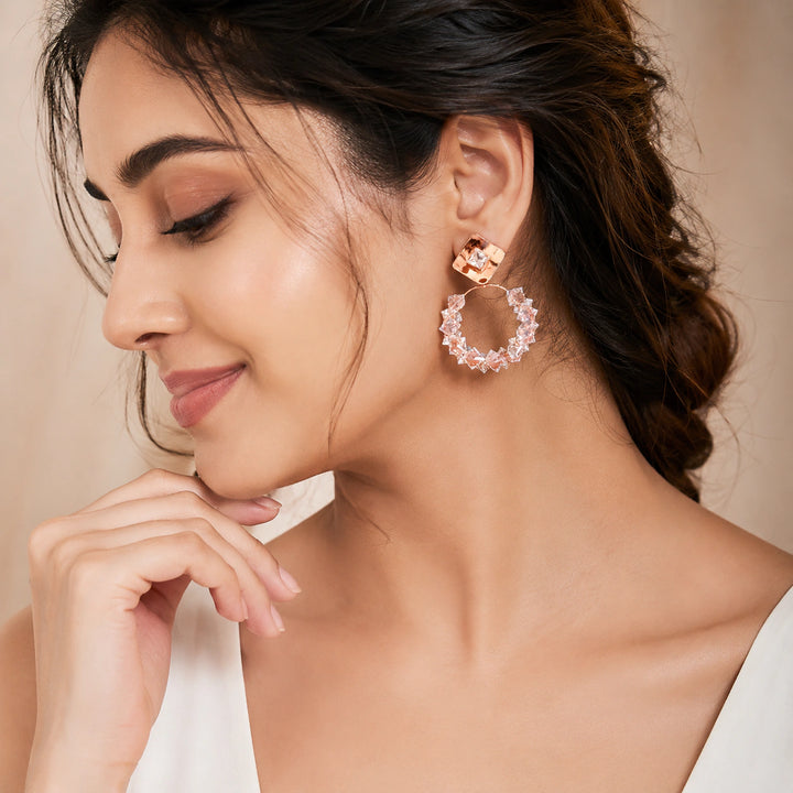 Rose-gold square crystal hoop earrings on a dark jewellery studio display