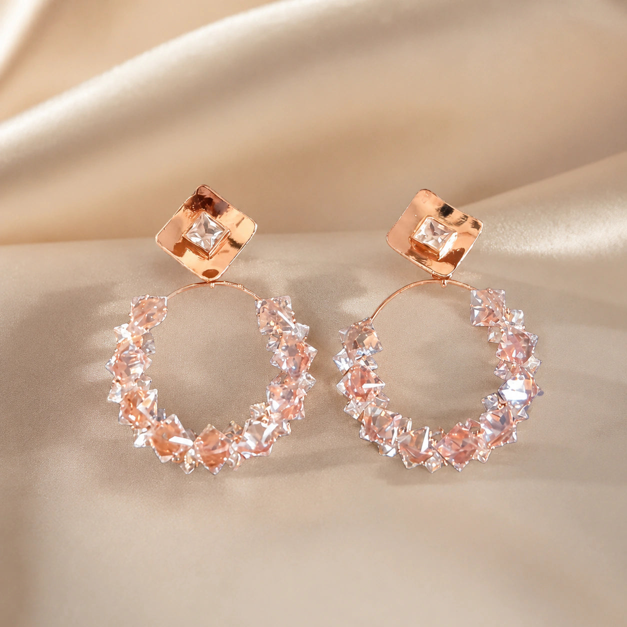 Rose-gold square crystal hoop earrings styled in an elegant jewellery flat lay