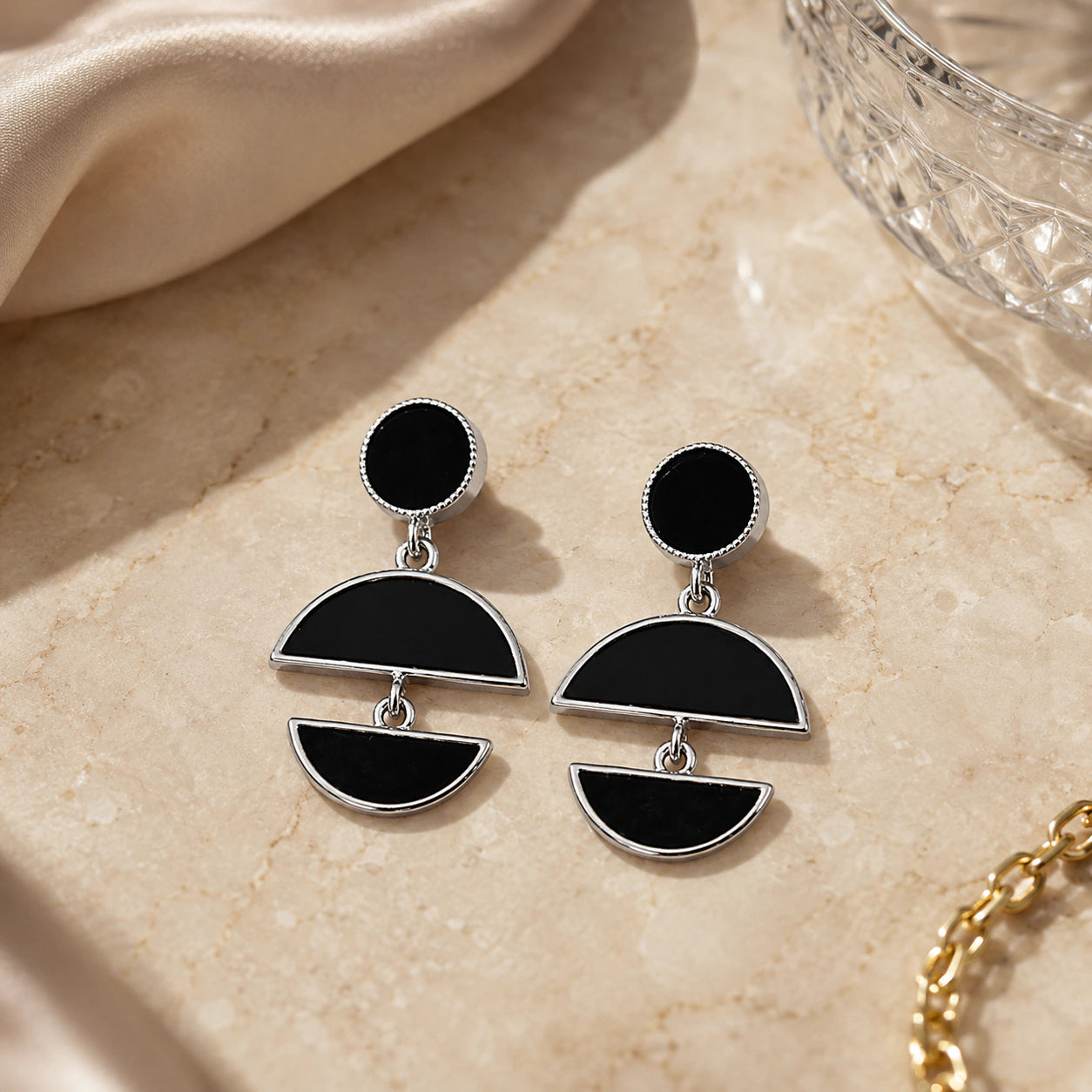 Close-up of black floral elements, silver hoops and pearl-style drops