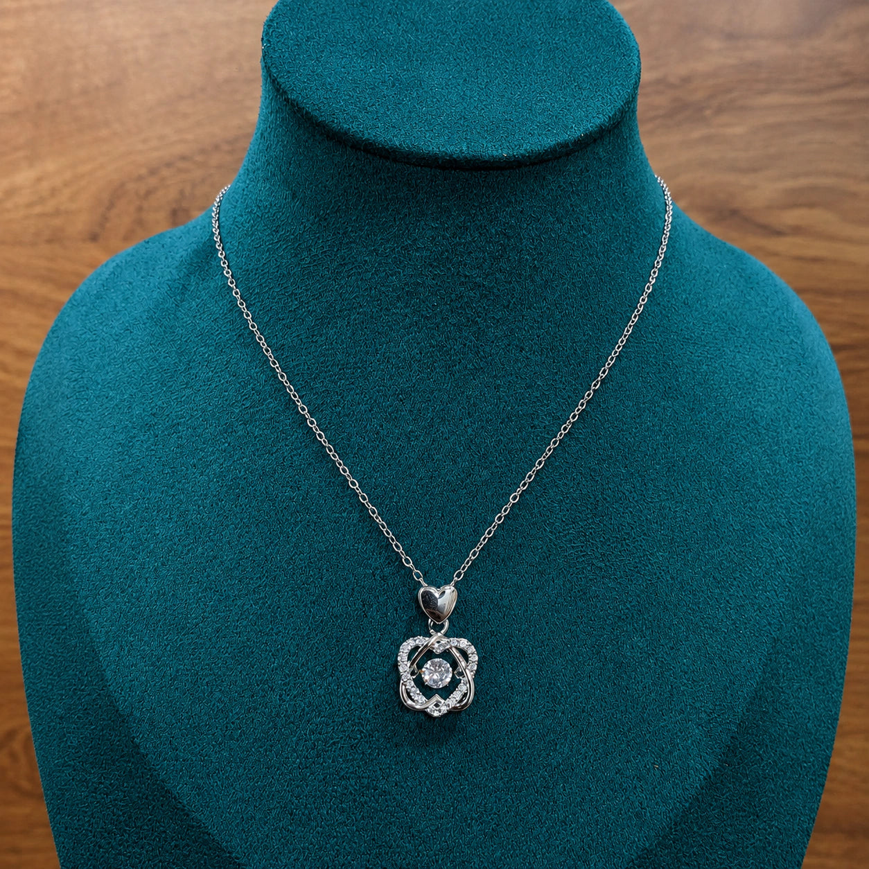 Silver interwoven heart necklace styled in an elegant jewellery flat lay