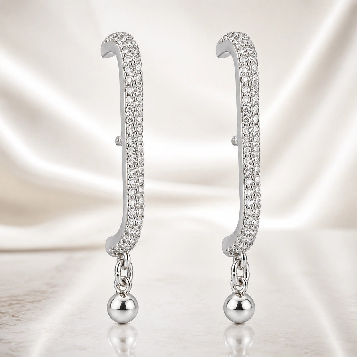 Silver curved-bar ball earrings styled in an elegant jewellery flat lay