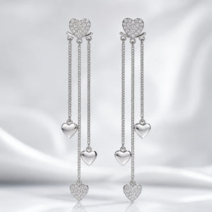 Silver heart triple-chain earrings styled in an elegant jewellery flat lay