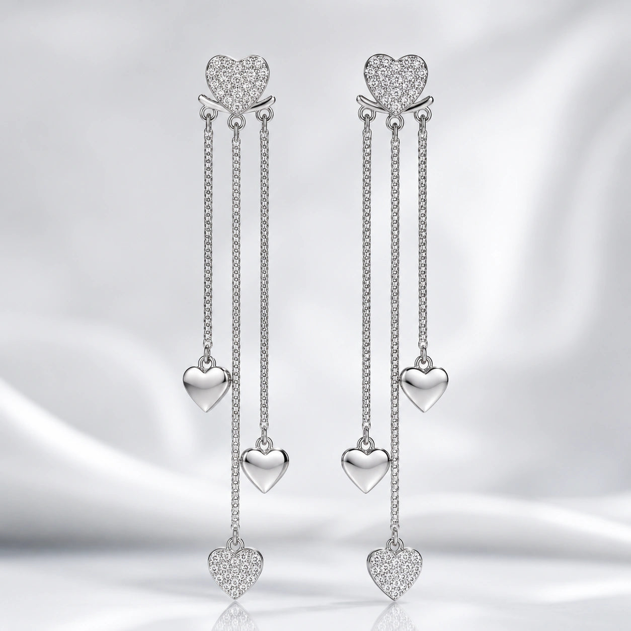 Silver heart triple-chain earrings styled in an elegant jewellery flat lay