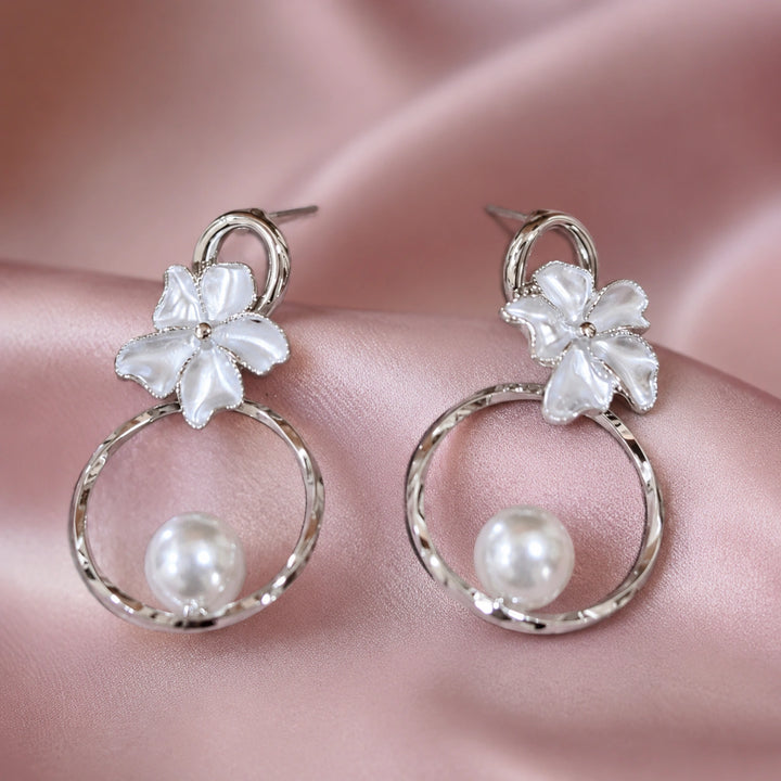 Silver pearl floral hoop earrings on a dark jewellery studio display