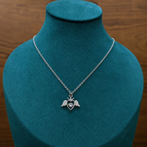 Silver winged heart necklace styled in an elegant jewellery flat lay