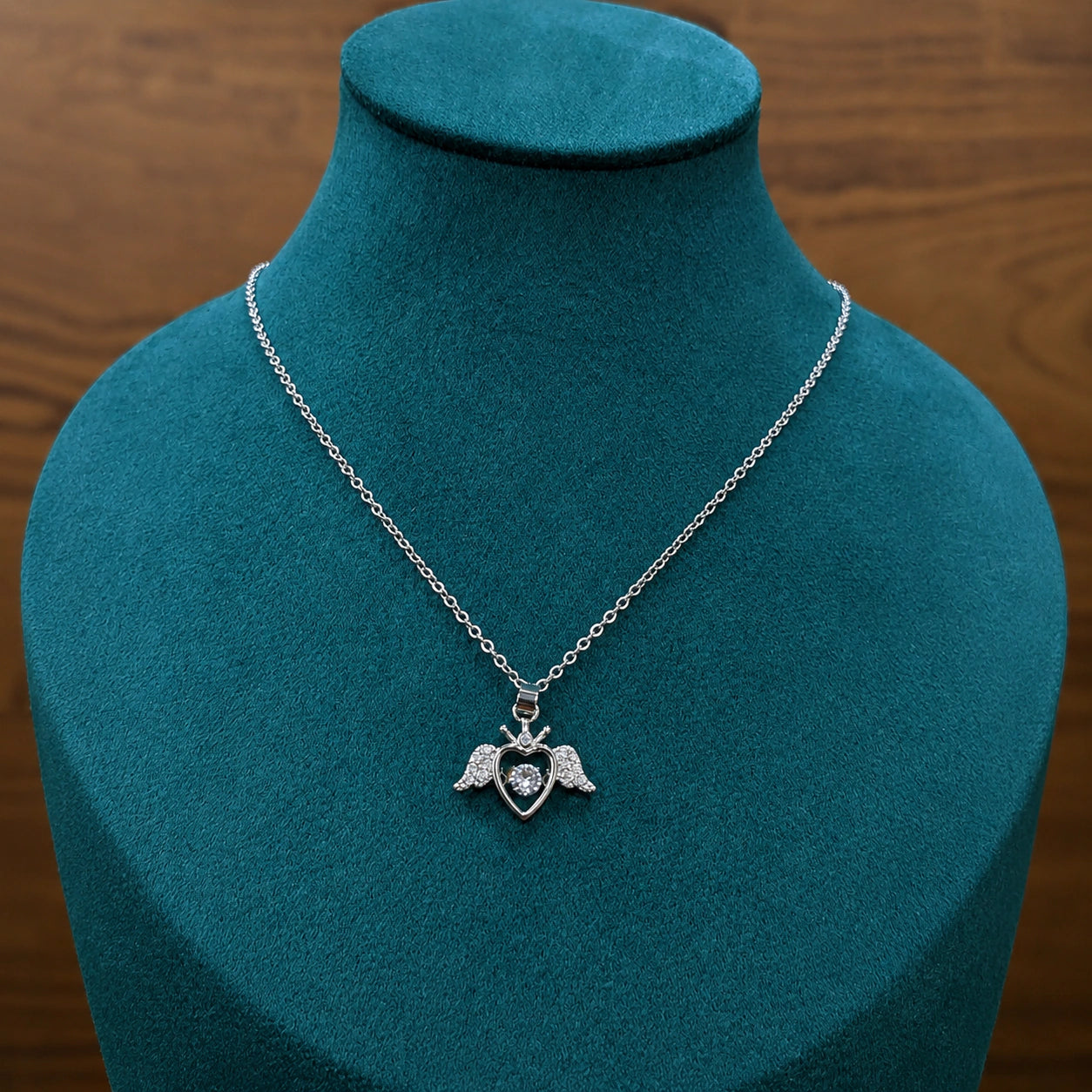 Silver winged heart necklace styled in an elegant jewellery flat lay