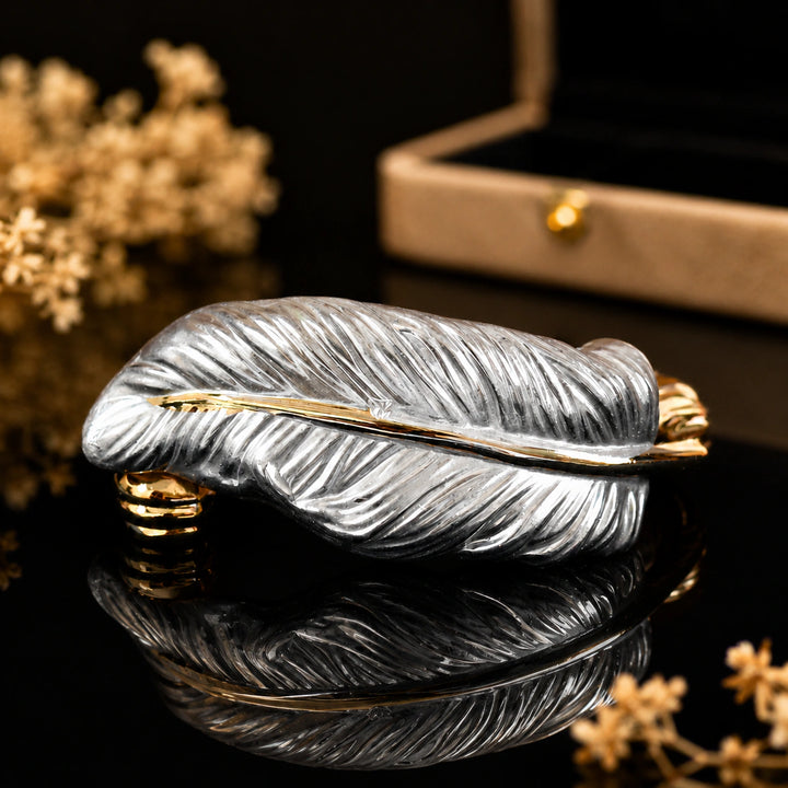 Two-tone engraved feather kada on a dark jewellery studio display
